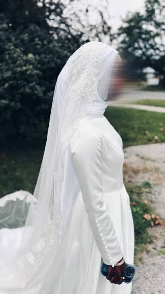 Back view of a bride in a long silk hijab wrap with one end falling past the shoulders like a short veil