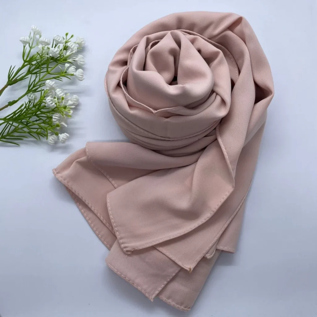 Folded hijabs in white, nude, beige, blush pink and gold laid out side by side