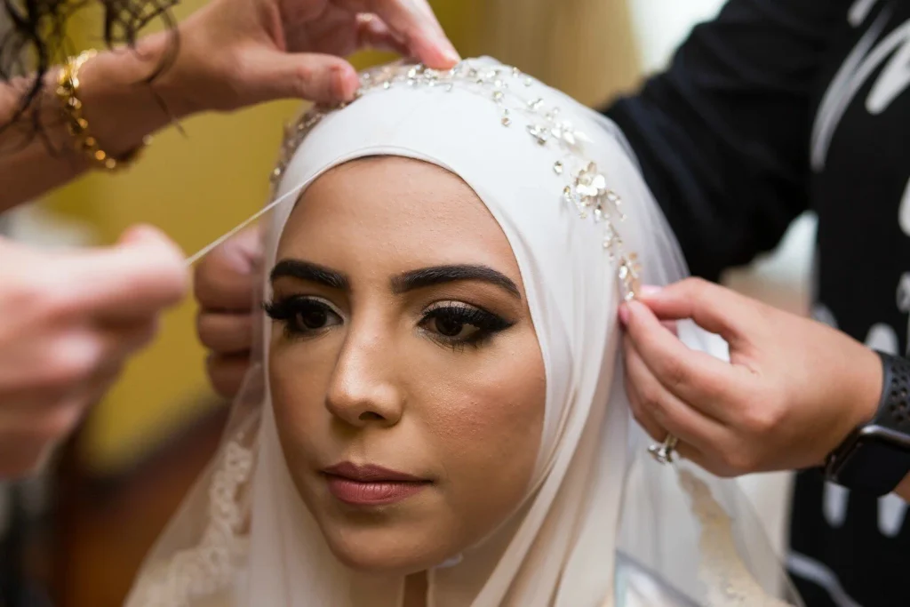 Bride in a white bridal hijab with an embellished veil being pinned in place